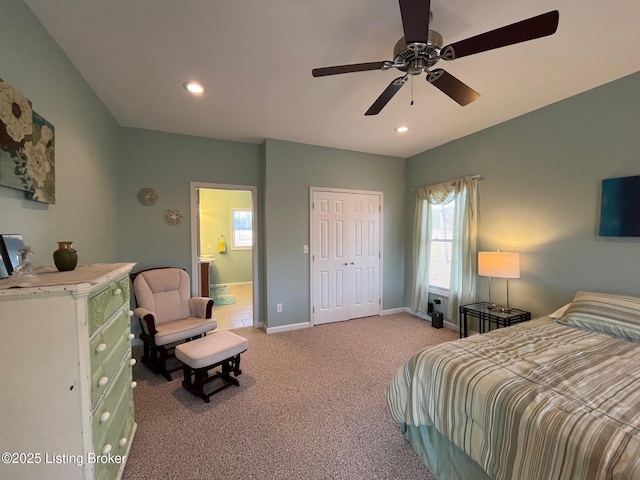 bedroom with connected bathroom, light carpet, ceiling fan, and a closet