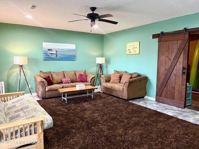 living room with a textured ceiling, a barn door, and ceiling fan