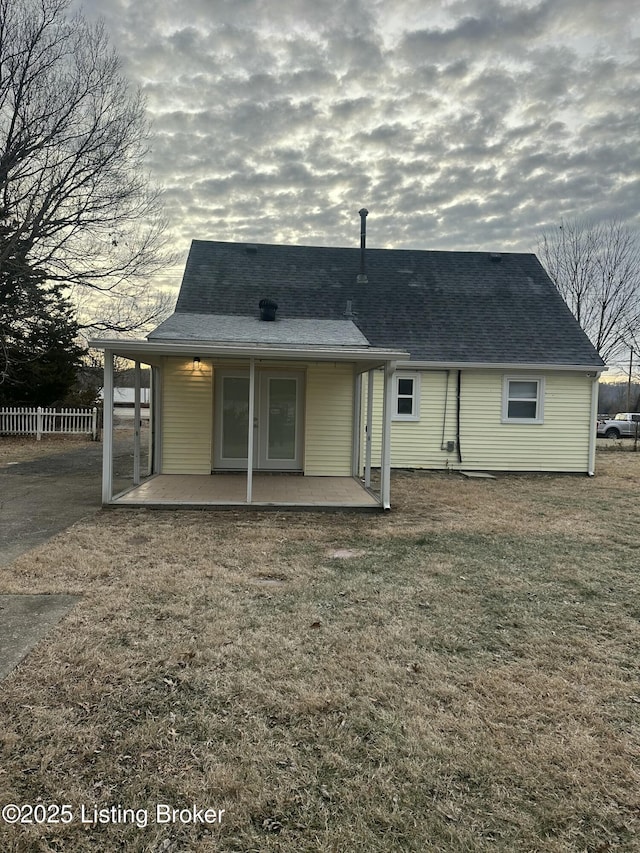 rear view of property with a yard, a patio, a shingled roof, and fence