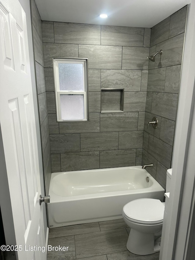 bathroom with toilet and tiled shower / bath combo