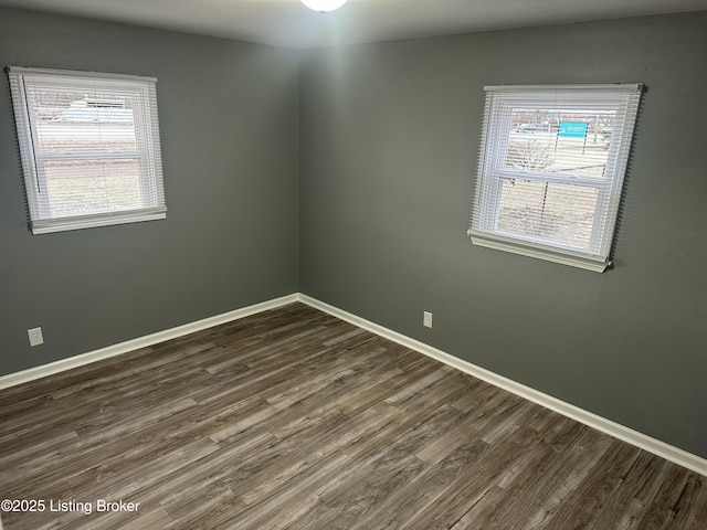 unfurnished room with dark wood finished floors and baseboards