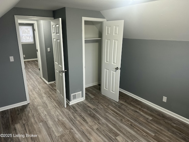 unfurnished bedroom featuring lofted ceiling, dark wood-type flooring, and a closet