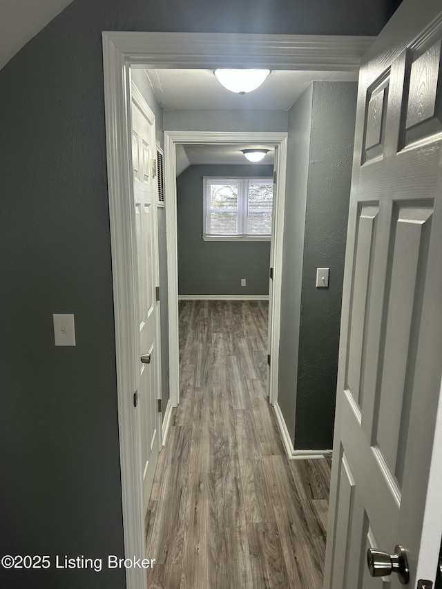 hallway with lofted ceiling and hardwood / wood-style flooring