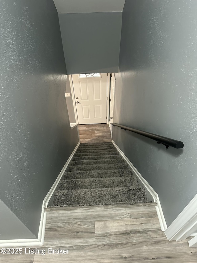 stairway featuring baseboards and wood finished floors