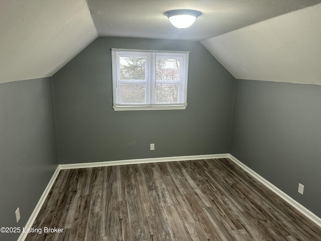 additional living space with dark hardwood / wood-style flooring and vaulted ceiling