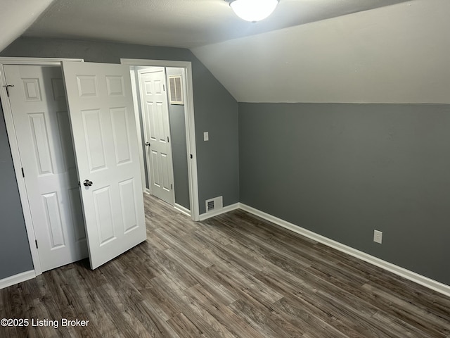 bonus room featuring vaulted ceiling, dark wood-type flooring, visible vents, and baseboards