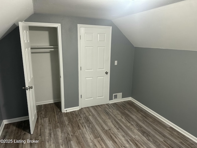 unfurnished bedroom with dark hardwood / wood-style floors, vaulted ceiling, and a closet