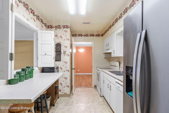 kitchen featuring white appliances, a kitchen breakfast bar, and white cabinets