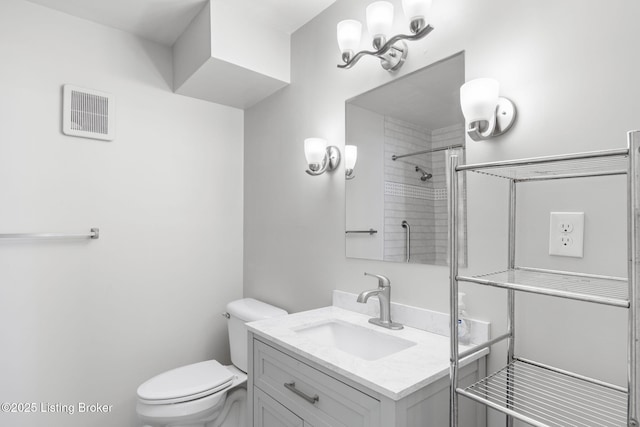 bathroom with vanity, toilet, and tiled shower