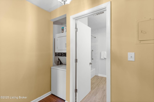 washroom with stacked washer / drying machine and light hardwood / wood-style flooring