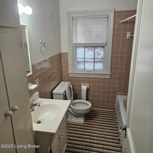 bathroom featuring tile patterned floors, vanity, toilet, and tile walls