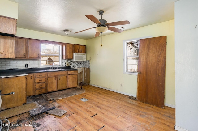 kitchen featuring sink, backsplash, ceiling fan, and light hardwood / wood-style flooring