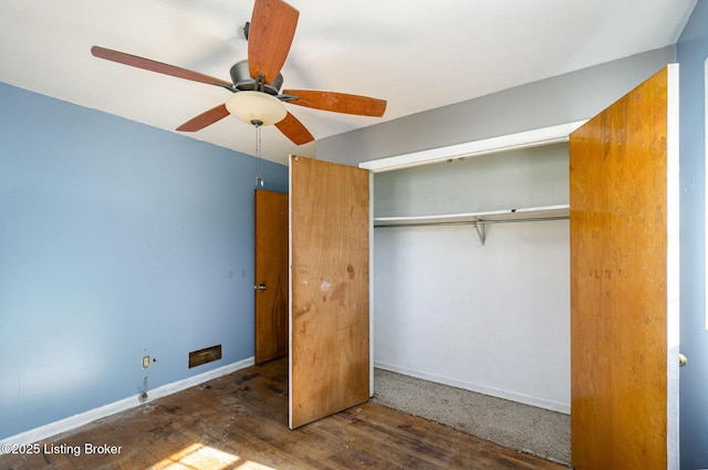 unfurnished bedroom with dark hardwood / wood-style flooring, a closet, and ceiling fan