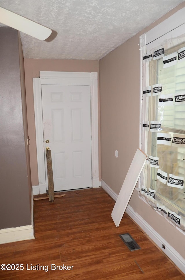 hallway featuring dark hardwood / wood-style flooring and a textured ceiling