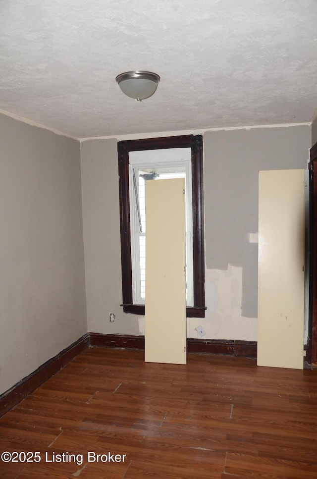 unfurnished room featuring dark hardwood / wood-style flooring and a textured ceiling