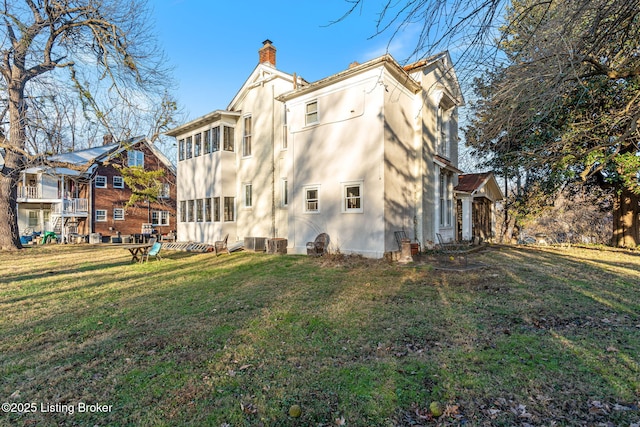 back of property featuring central air condition unit and a lawn