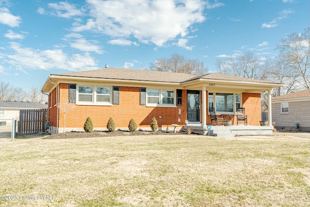 view of front facade featuring brick siding, a front lawn, and fence