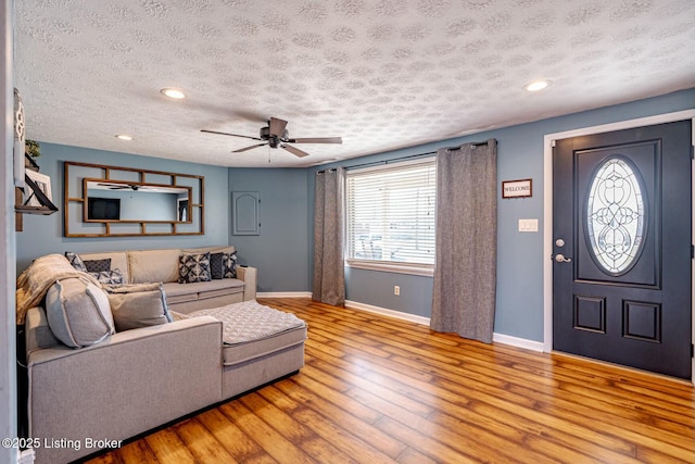 living area with baseboards, light wood-style flooring, ceiling fan, a textured ceiling, and recessed lighting