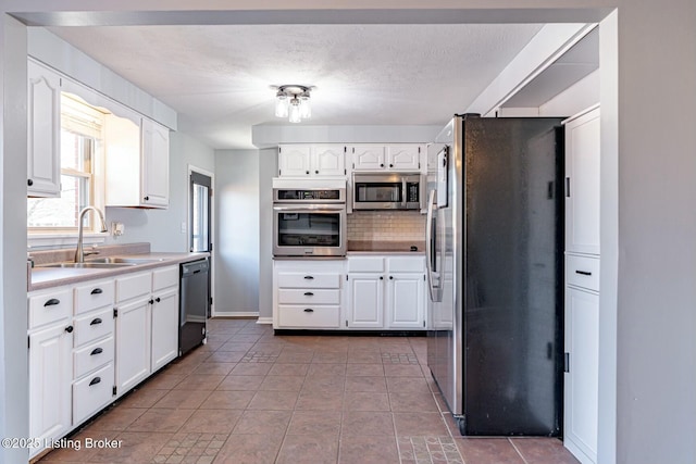 kitchen featuring appliances with stainless steel finishes, light countertops, white cabinets, and a sink