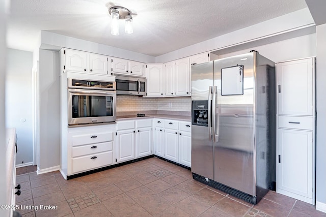 kitchen featuring white cabinets, a textured ceiling, stainless steel appliances, and backsplash