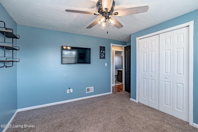 unfurnished bedroom with carpet, visible vents, a textured ceiling, and baseboards