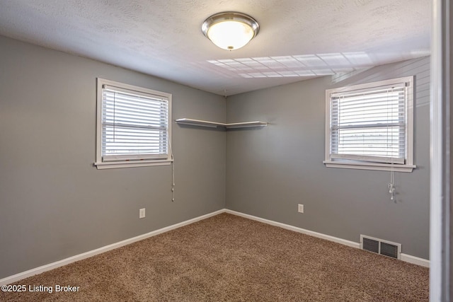 carpeted empty room featuring baseboards, visible vents, and a healthy amount of sunlight