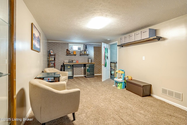 interior space with a textured ceiling, beverage cooler, brick wall, carpet flooring, and visible vents