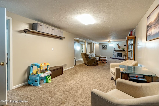 game room featuring a textured ceiling, a fireplace, visible vents, baseboards, and carpet