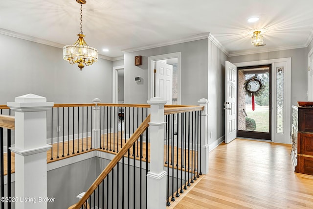 foyer entrance with ornamental molding, light hardwood / wood-style floors, and a notable chandelier