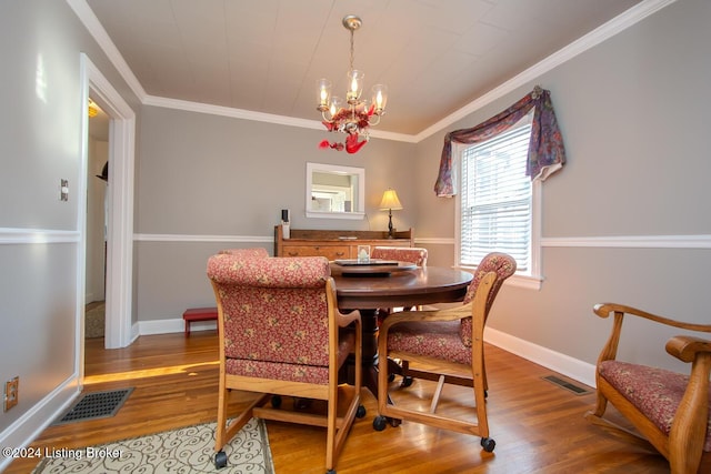 dining area with crown molding, hardwood / wood-style floors, and an inviting chandelier