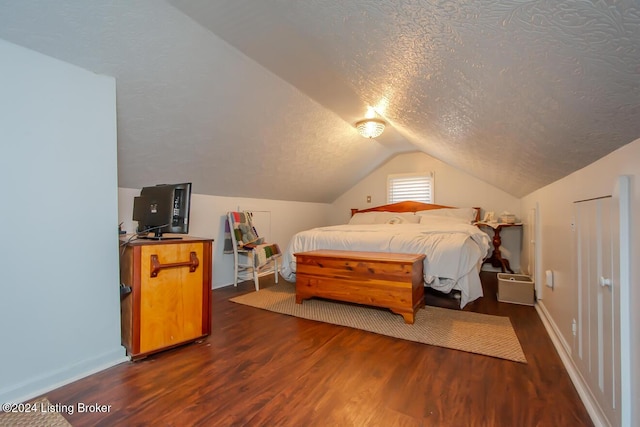 bedroom featuring dark hardwood / wood-style flooring, vaulted ceiling, and a textured ceiling