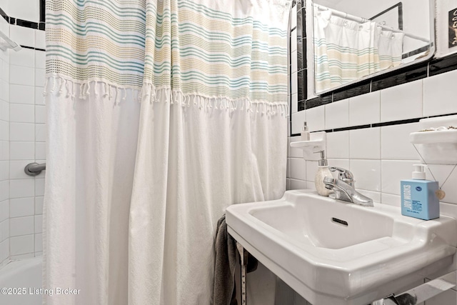 bathroom with shower / bath combo, sink, tile walls, and backsplash