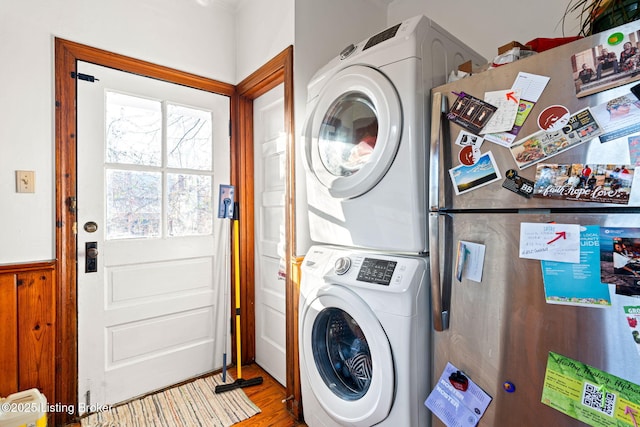 laundry room with stacked washing maching and dryer and hardwood / wood-style floors