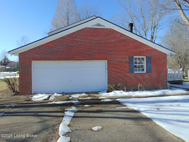 view of snowy exterior featuring a garage and an outbuilding