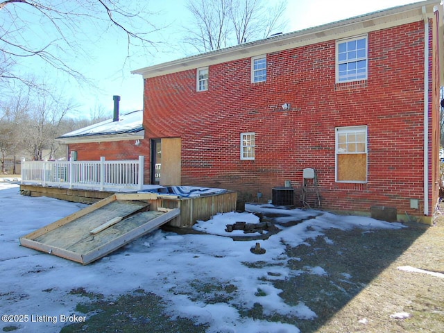 snow covered rear of property featuring central AC and a deck