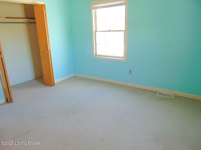 unfurnished bedroom featuring light carpet and a closet