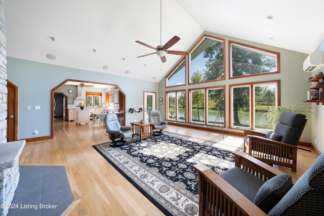 living room featuring a water view, a wall mounted AC, high vaulted ceiling, ceiling fan, and light hardwood / wood-style floors