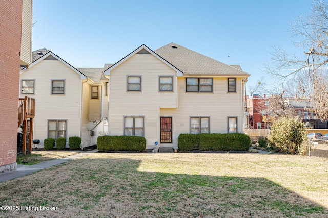 multi unit property featuring a shingled roof and a front yard