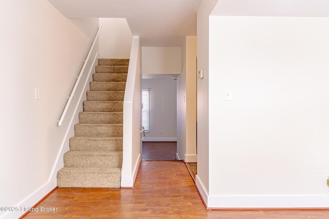 staircase featuring baseboards and wood finished floors