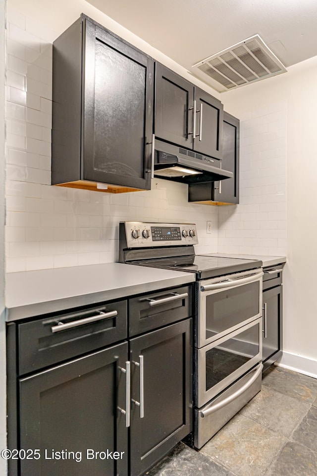 kitchen featuring visible vents, decorative backsplash, double oven range, under cabinet range hood, and baseboards