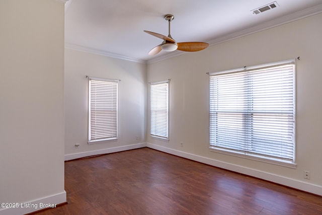 empty room featuring a healthy amount of sunlight, visible vents, and crown molding