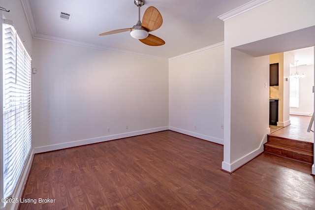 spare room featuring ornamental molding, ceiling fan with notable chandelier, baseboards, and wood finished floors