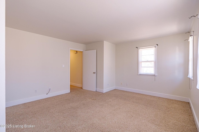 carpeted empty room featuring baseboards