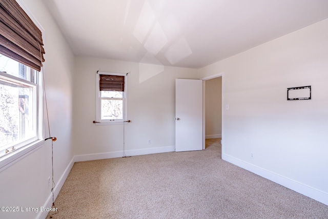 unfurnished room with baseboards and light colored carpet