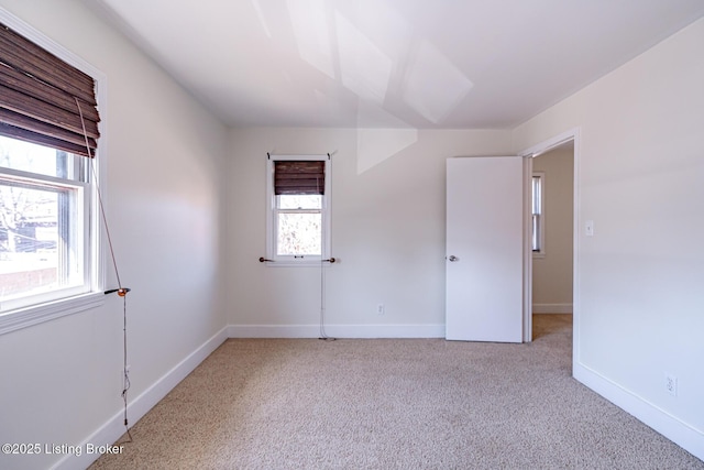 spare room with baseboards and light colored carpet