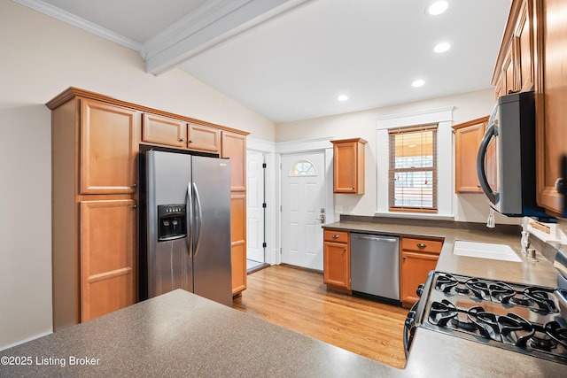 kitchen featuring ornamental molding, stainless steel appliances, lofted ceiling with beams, and light wood-type flooring