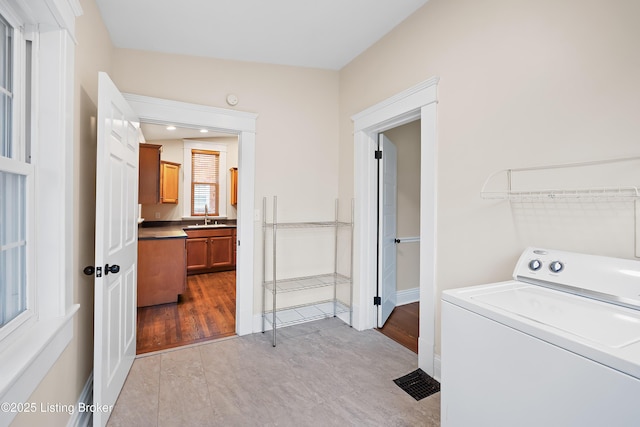 laundry area with washer / clothes dryer, sink, and light hardwood / wood-style flooring