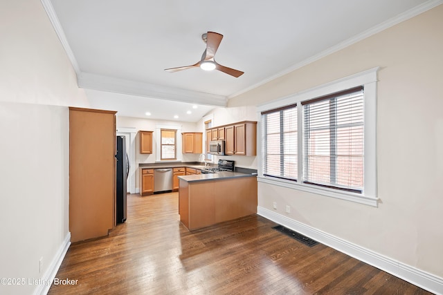 kitchen featuring dark wood-type flooring, ceiling fan, stainless steel appliances, ornamental molding, and kitchen peninsula