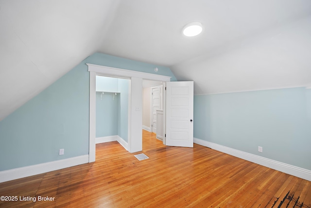 additional living space with vaulted ceiling and light hardwood / wood-style floors