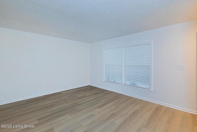 unfurnished room with hardwood / wood-style floors and a textured ceiling